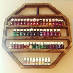 a shelf filled with lots of bottles of essential oils on top of a white wall