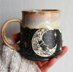 a hand holding a coffee mug with a moon and stars painted on the inside of it