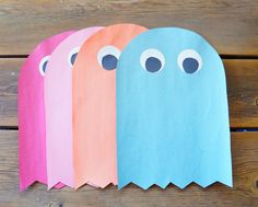 four paper ghost bags sitting on top of a wooden table