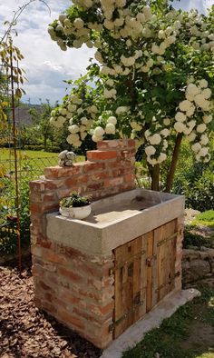 an outdoor kitchen made out of bricks with flowers growing on the outside and in front