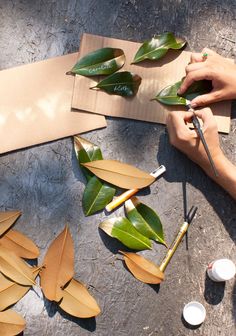 a person is painting leaves on a piece of cardboard