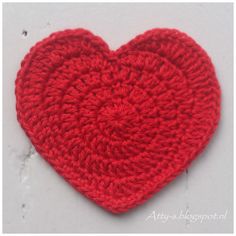 a crocheted red heart on a white surface