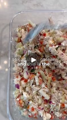 a plastic container filled with food on top of a white marble countertop next to a blue spoon