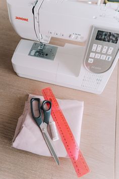 a pair of scissors sitting on top of a piece of cloth next to a sewing machine