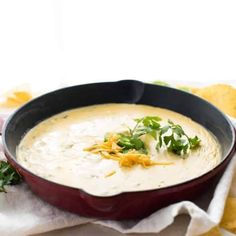 a bowl of soup with broccoli and cheese on the side next to some bread