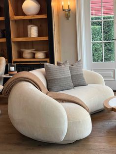 a living room filled with furniture and a book shelf next to a large open window