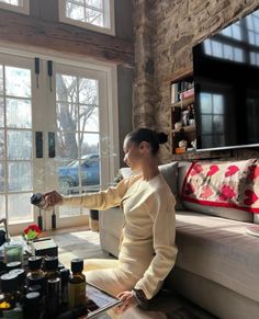 a woman sitting on the floor in front of a window with lots of bottles around her