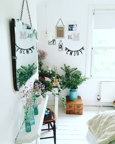 a white room with flowers and plants in vases on the wall next to a mirror