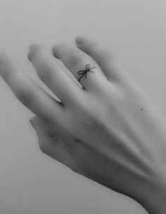 a person's hand with a small spider tattoo on their left wrist and fingers