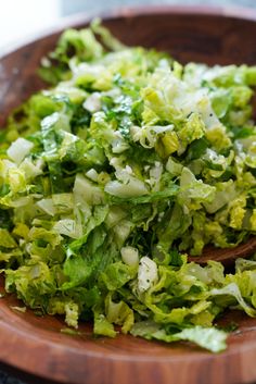 a wooden bowl filled with lettuce on top of a table