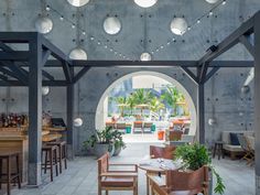 the inside of a restaurant with tables, chairs and potted plants hanging from the ceiling