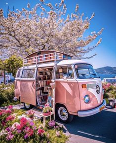 an old vw bus is parked in front of some flowers