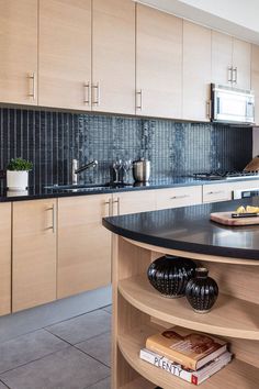 a kitchen with black counter tops and wooden cabinetry, along with an island in the middle