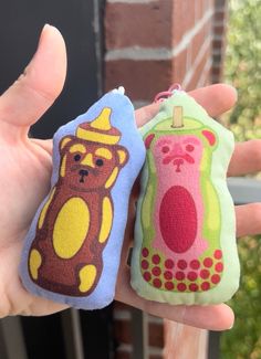 two small cell phones are in the palm of someone's hand, one has a bear on it