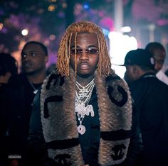 a man with dreadlocks standing in front of other people on the street at night