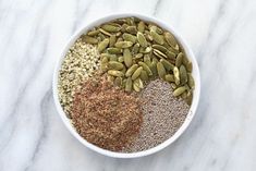 a white bowl filled with seeds and seasoning on top of a marble countertop