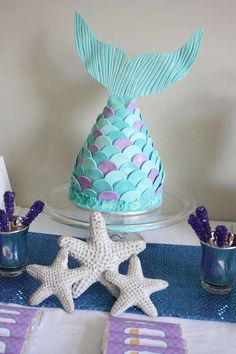 there is a cake decorated like a mermaid tail and three starfishs on the table