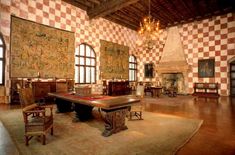 a large room with checkered walls and wooden tables in the center, two chandeliers hanging from the ceiling