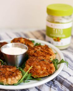 crab cakes on a white plate with a small bowl of ranch dressing next to it