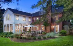 a large white house with an outdoor dining table and chairs in the front yard at night