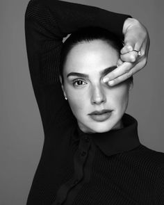 a black and white photo of a woman with her hands on her head, looking at the camera