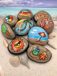 a pile of painted rocks sitting on top of a sandy beach next to the ocean