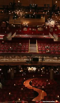 an empty auditorium with red seats and chandeliers