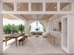 an outdoor living area with stone walls and wood ceilinging, along with white furniture