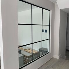 an empty room with some glass windows in the wall and wood flooring on the other side