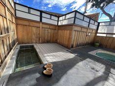 there is a hot tub in the middle of this backyard with wooden walls and flooring