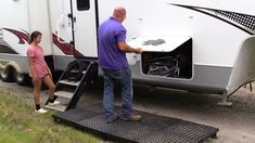 a man and woman loading an rv into the trailer