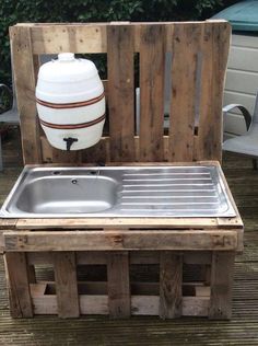 an outdoor sink made out of wooden pallets with a large white container on top