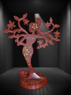 a red sculpture in the shape of a tree with pink flowers and leaves on it