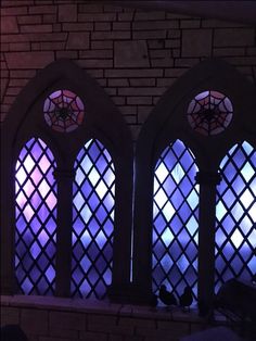 three stained glass windows with spider webs on them in a brick wall and ceiling