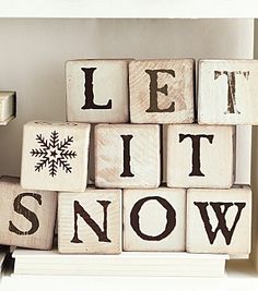 wooden blocks spelling let it snow on top of each other in front of a shelf