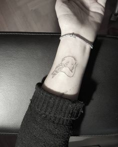 a woman's wrist with a small tattoo on the left side of her arm