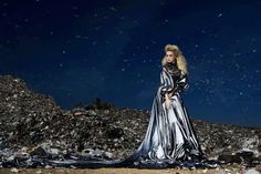 a woman standing on top of a pile of garbage next to a sky filled with stars