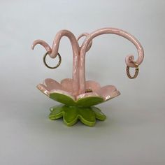 a pink and green flower shaped vase sitting on top of a table