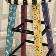 four wooden stools with different designs on the top and bottom, all painted in different colors