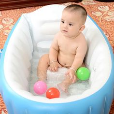 a baby sitting in an inflatable pool with balls