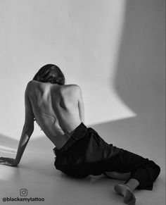 black and white photograph of a woman sitting on the floor with her back to the camera