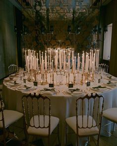 a table with many chairs and candles on it