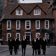 a group of men in suits walking down a street next to a tall brick building