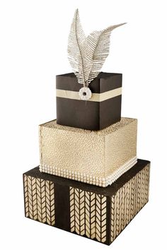 three tiered cake with black and white designs on the top, decorated with silver leaves