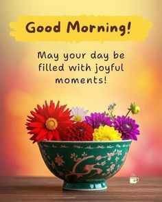 a green bowl filled with colorful flowers on top of a wooden table next to a sign that says good morning