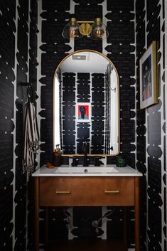 a bathroom with black and white wallpaper has a mirror on the vanity next to it