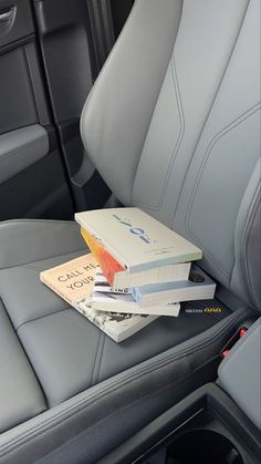 three books are stacked on top of each other in the back seat of a car