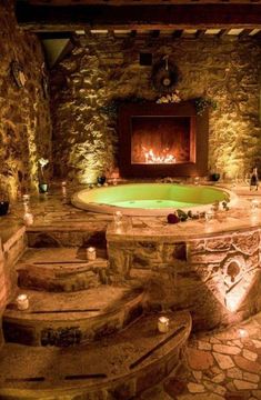 an indoor hot tub surrounded by stone walls and steps leading up to the fire place