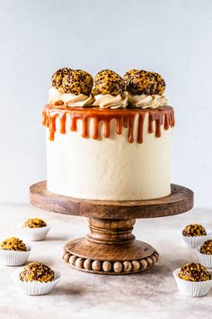 a cake with caramel drizzled on top and cupcakes next to it