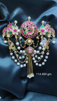 a close up of a brooch on a blue satin material with pearls and beads